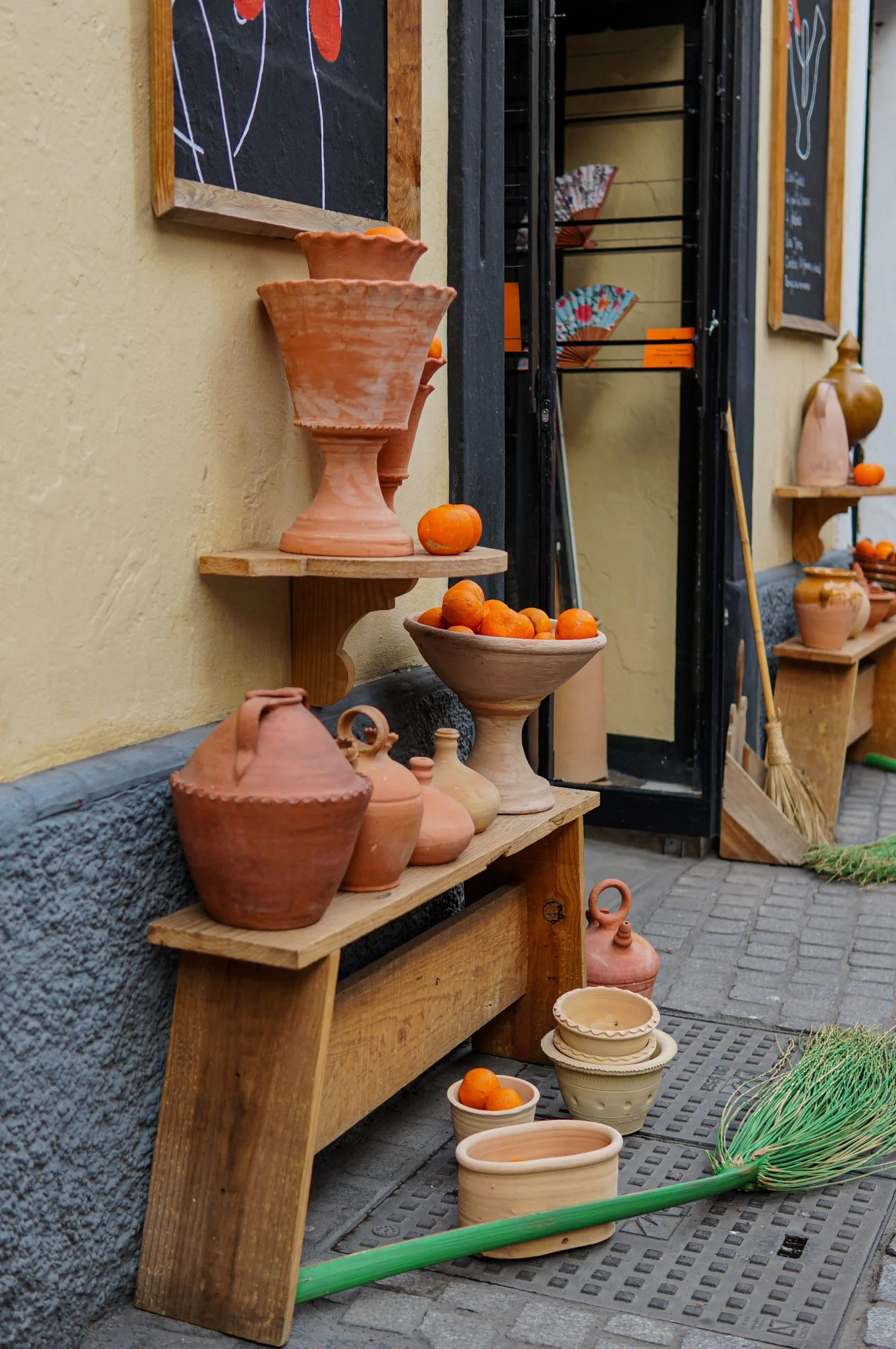Terracotta pots on wooden benches outside a small shop