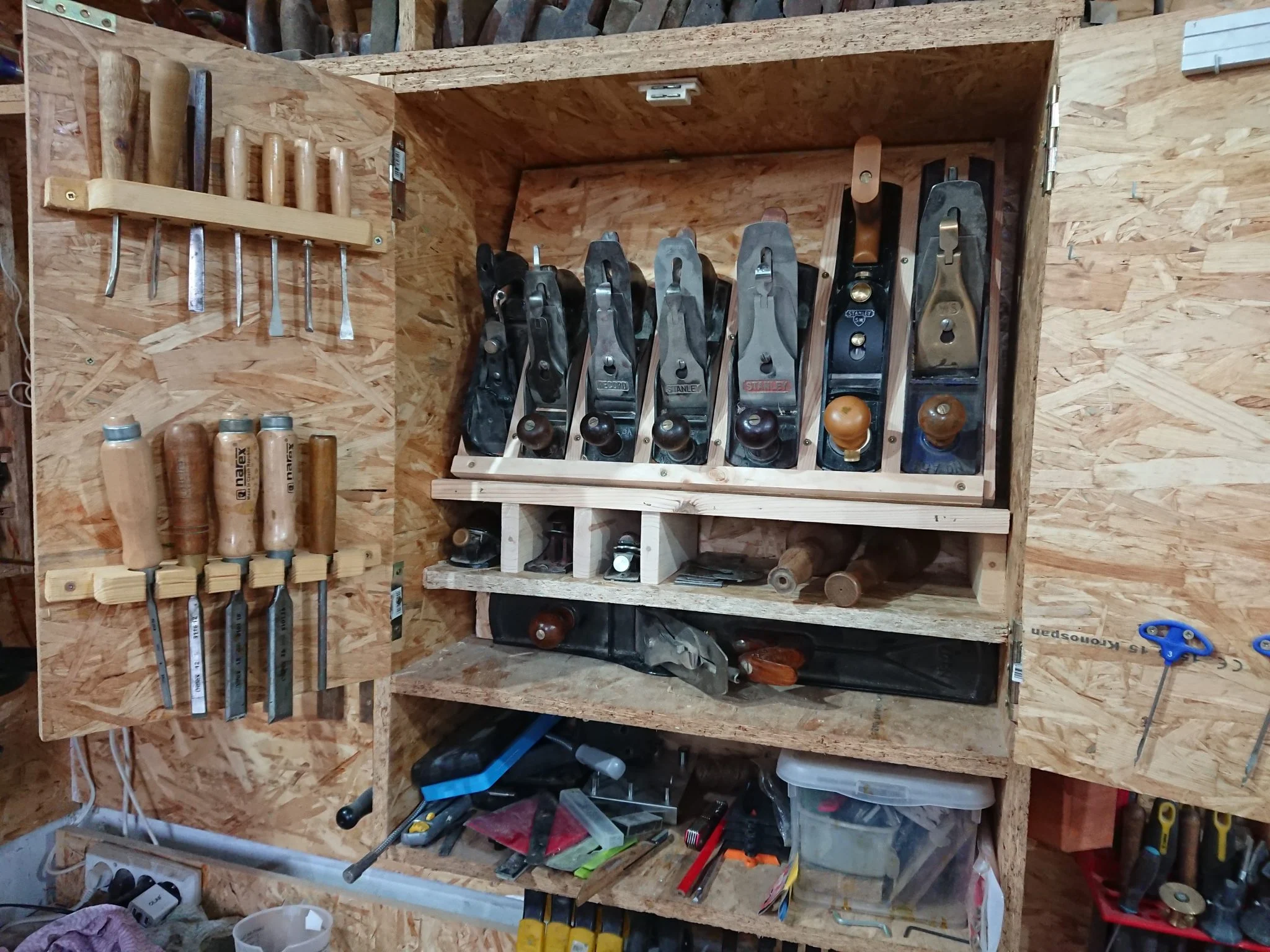 A plywood tool cabinet with hand planes and chisels